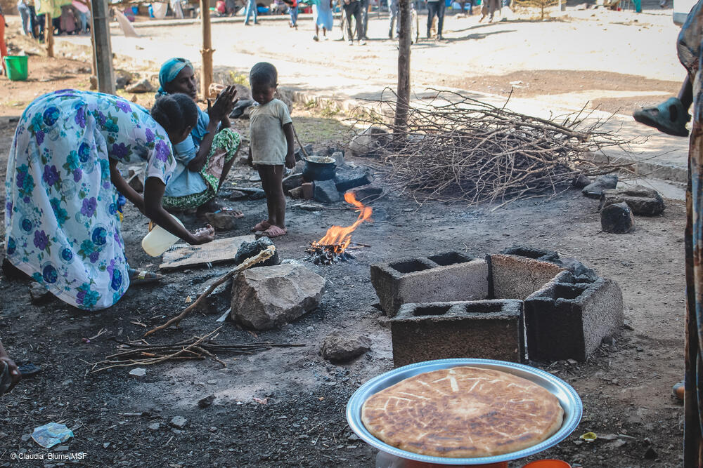 msb58246_medium.jpg Cooking on makeshift stoves outside. As the only donation most people have received is wheat, they eat bread every day.