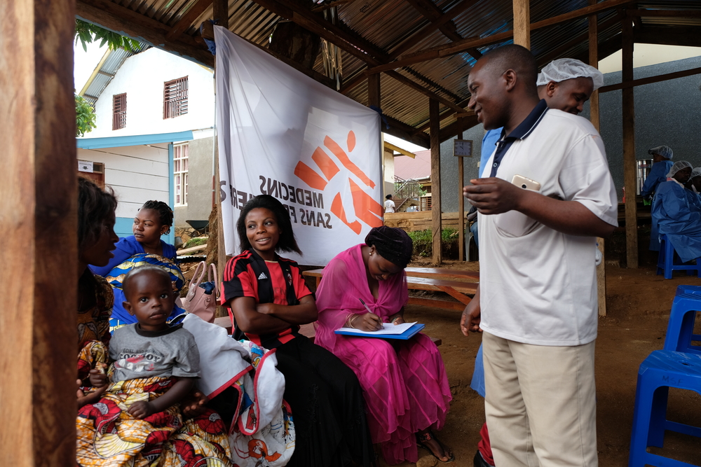 Joseph MbokaniI Kambale, a sensitizing agent with the national Ebola response, answers to questions from people waiting to get vaccinated. Fears and misconceptions keep many eligible participants from getting the vaccine. [© MSF/Samuel Sieber]