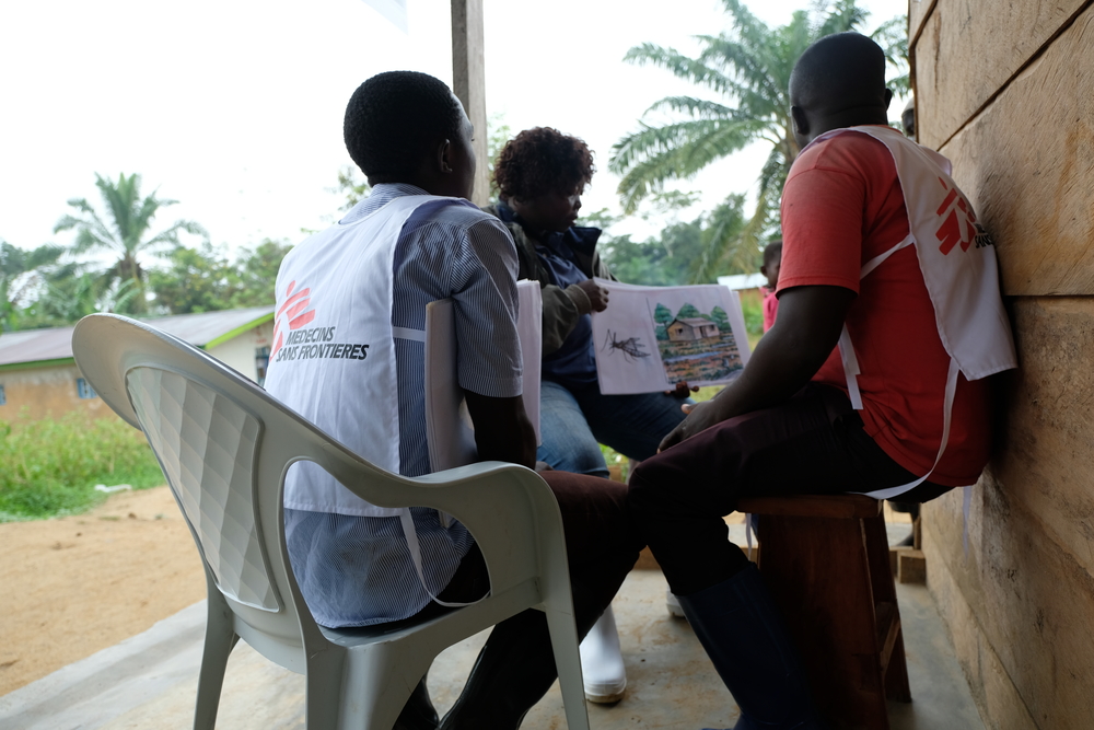 MSF Community Outreach Specialist Wivine Bokotogi shows a set of flashcards on malaria prevention and treatment to two local health promoters. [Photo: Samuel Sieber/MSF ]