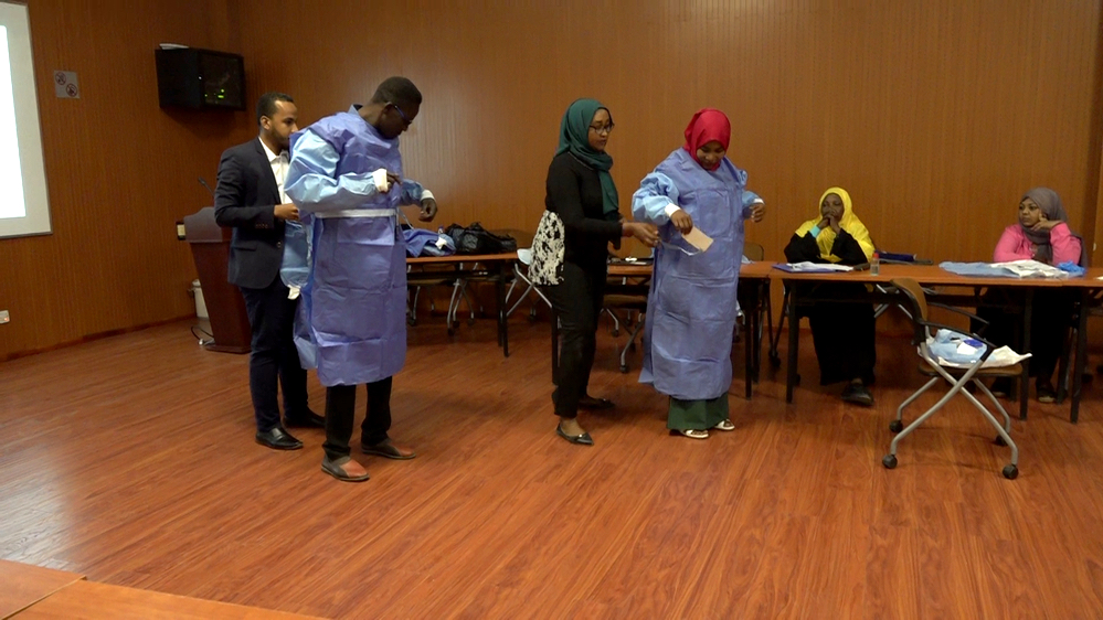 Sudanese healthcare professionals try to put on personal protection equipment (PPE) during a training by