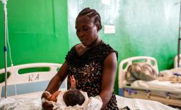 Resimène, 39 y.o, is holding her new-born baby on her bed in the MSF supported Isaïe Jeanty Maternity in Port-au-Prince
