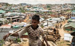 A Rohingya man carries wood through the Kutupalong- Balu Khali mega camp. Cox’s Bazar District, Bangladesh. [© Robin Hammond/NOOR ]