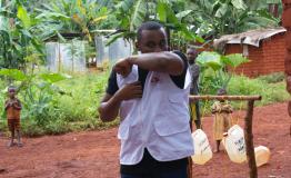 Tumaini Kombe, focal point for health promotion in Nduta explaining sneeze & cough etiquette