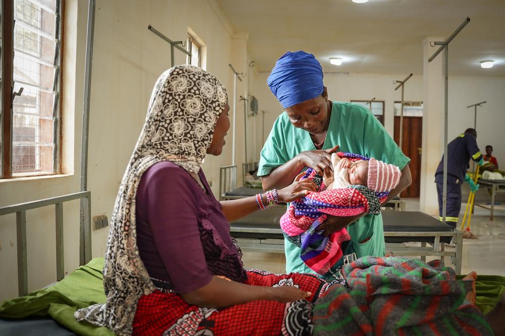 Nurse aide Ndayumvire Antoinette holds a baby while interacting with the mother in the maternity ward at the MSF Hospital in Nduta Camp.