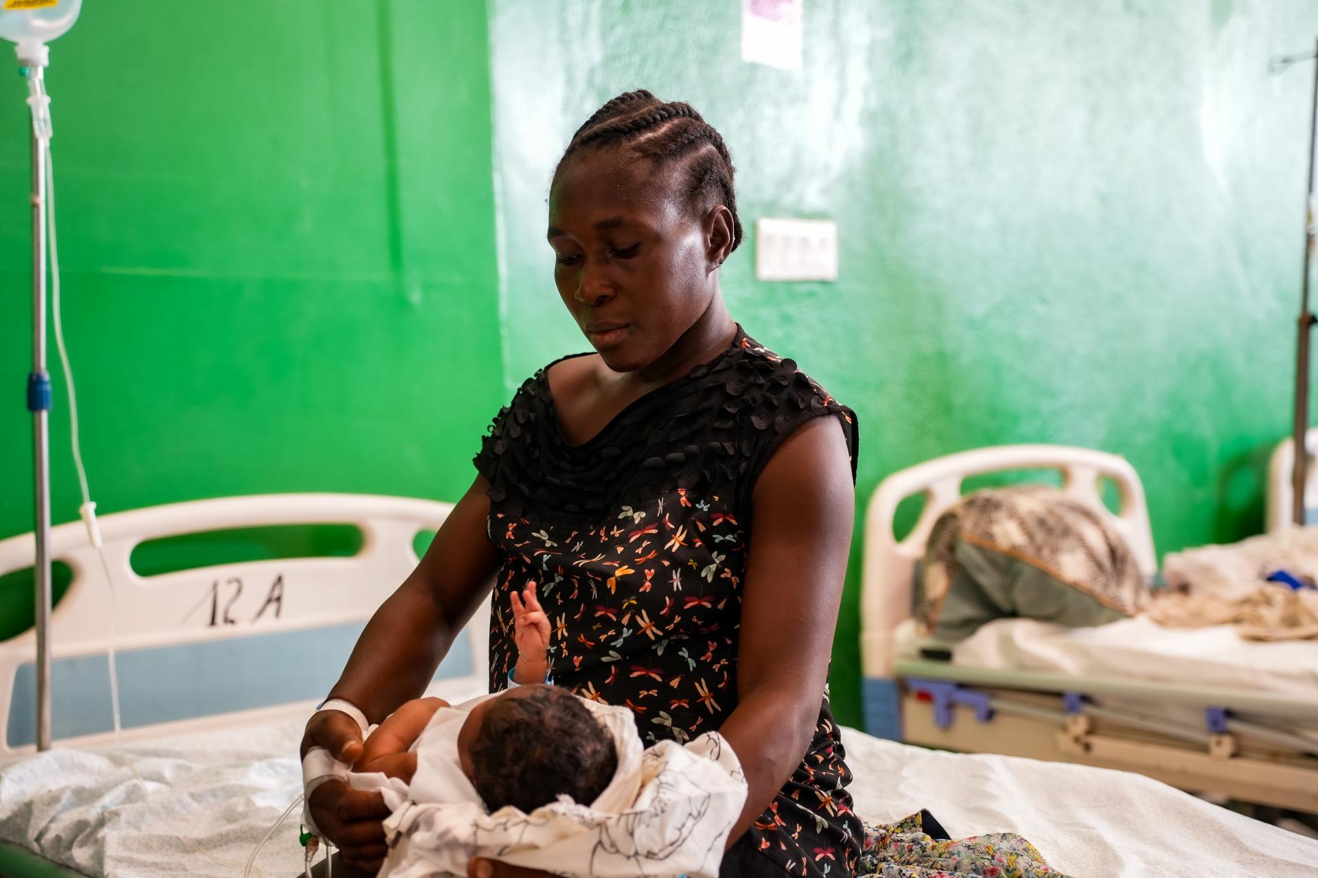 Resimène, 39 y.o, is holding her new-born baby on her bed in the MSF supported Isaïe Jeanty Maternity in Port-au-Prince