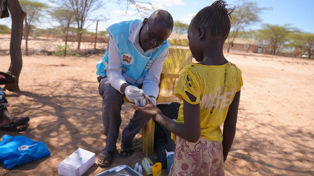 David Ekeru, a community health promoter, tests a child for malaria at their home using the test and treat approach in Namakane village, Turkana, Kenya.