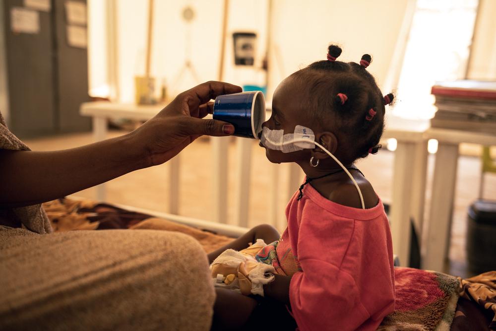 Amna Abderahim (not visible), 21, a Sudanese refugee who fled the 2023 massacres in El Geneina (Sudan), gives water to her daughter Djout Mahamat, 11 months old