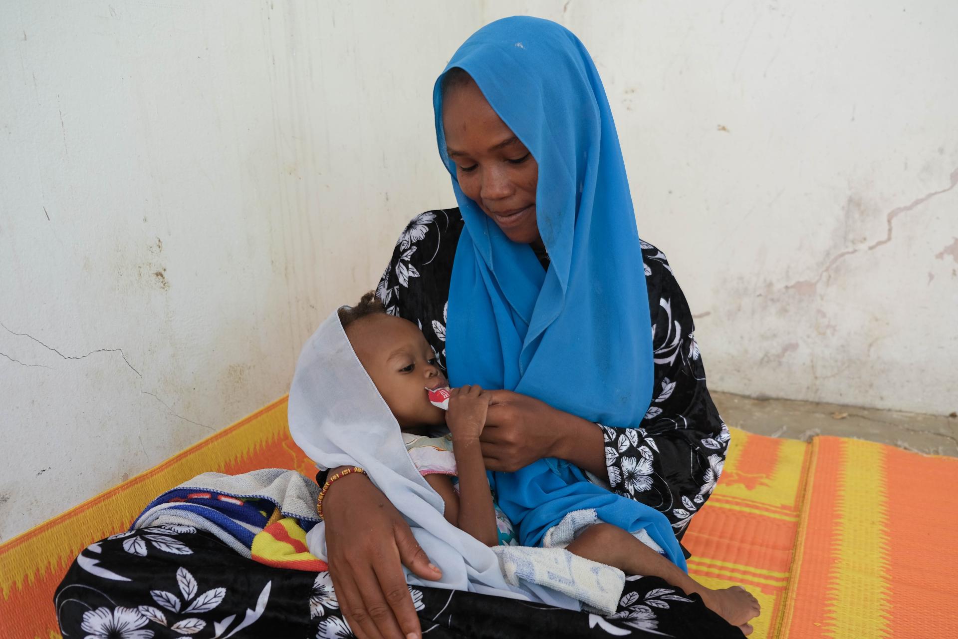 After receiving Plumpy’Nut at the Amsinéné health center supported by MSF for nutritional care, this mother gives the Plumpy’Nut to her daughter.