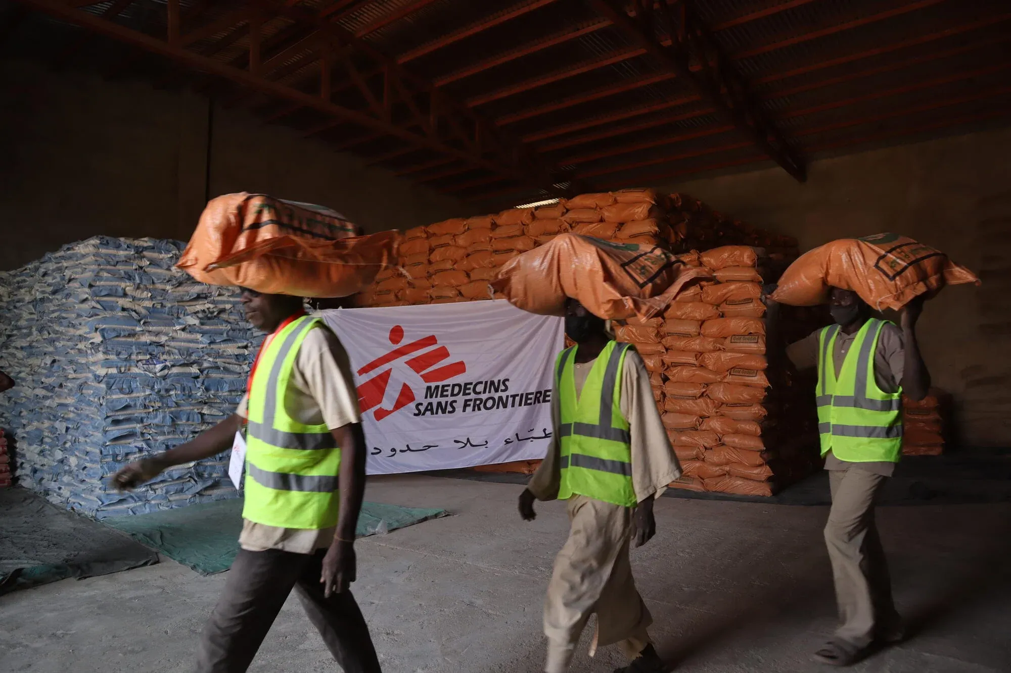 Staff at an MSF warehouse carry food items to a truck headed towards a food distribution site in Nyala, South Darfur. Sudan, February 2025.
