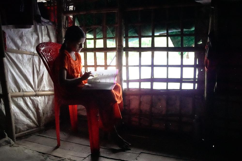 A Rohingya girl studies in her shelter, Bangladesh, June 2025.