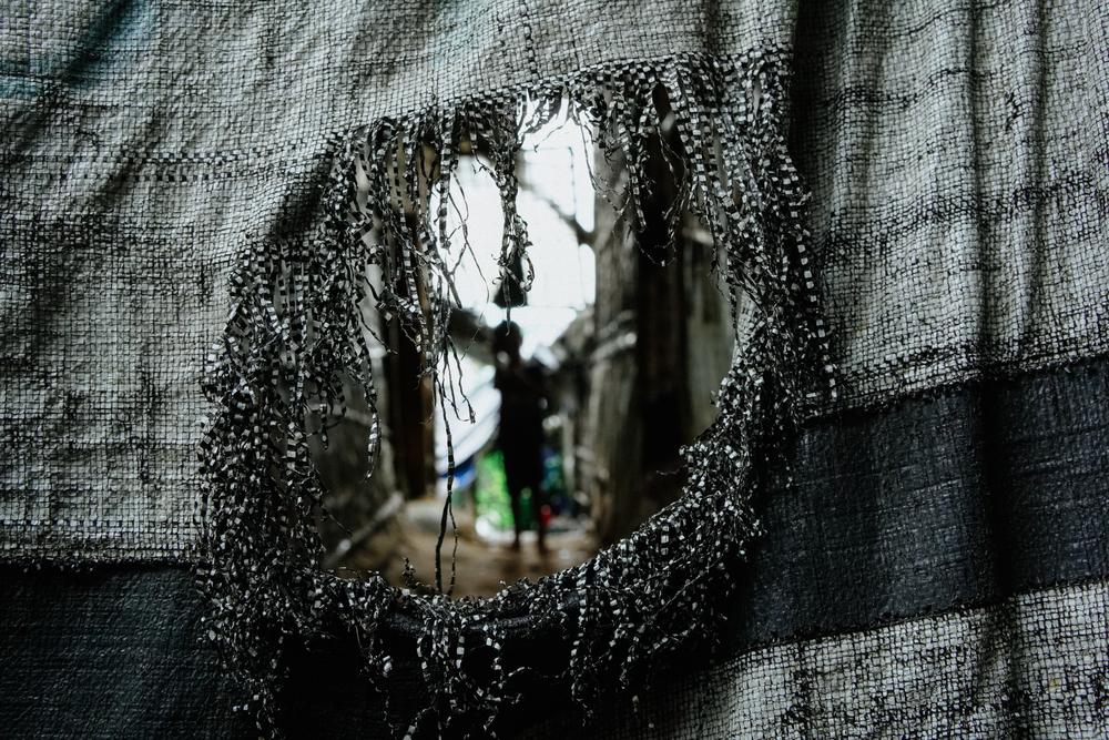 A young child, seen through tarpaulin. Bangladesh, June 2025.