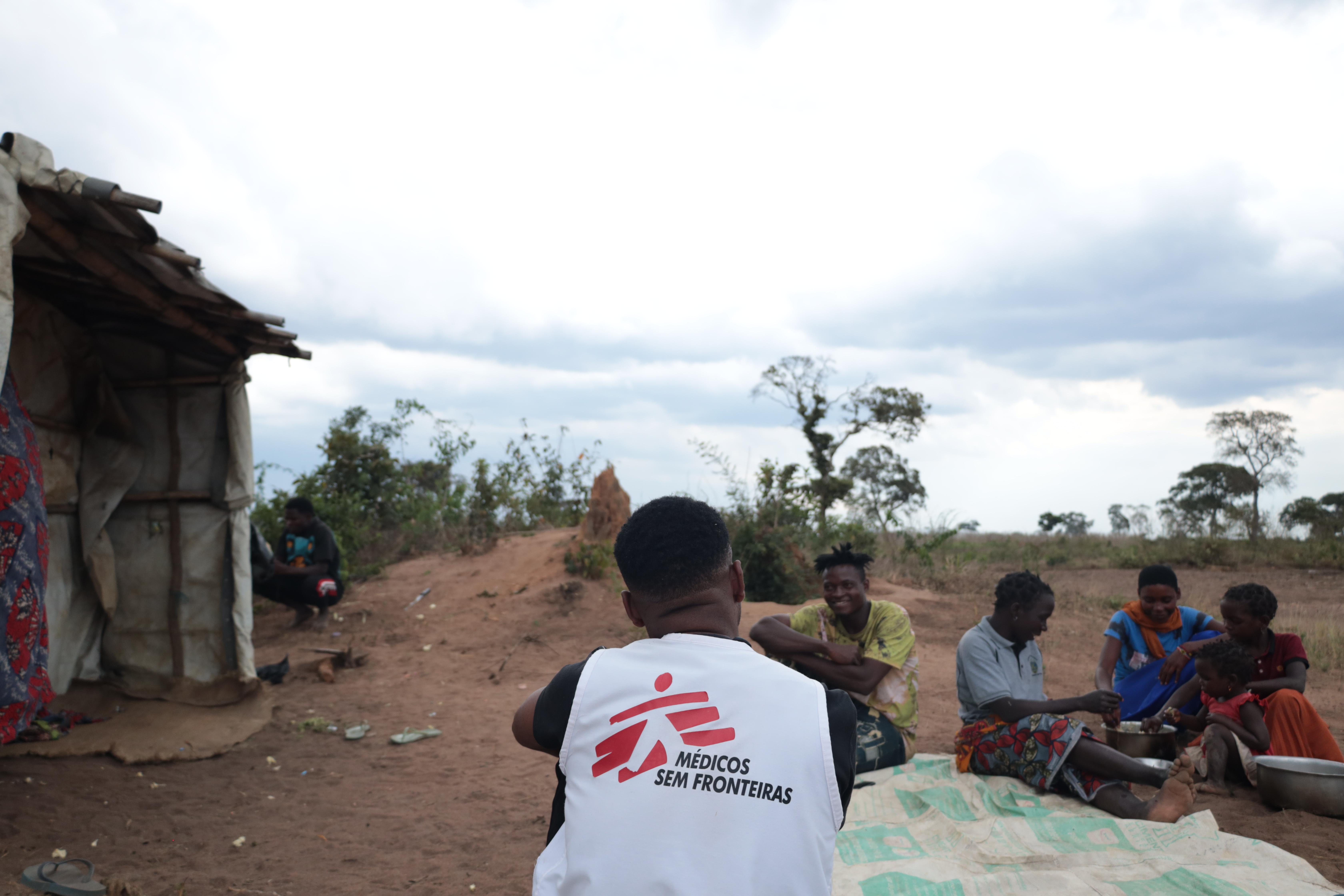 MSF Health Promoter Luis João Chauque talks to Saidia Albino and his family outside their shelter in Eduardo Mondlane camp. The family of five had just arrived after a 3-day walk from Mocímboa da Praia, fleeing out of fear of increased attacks. 