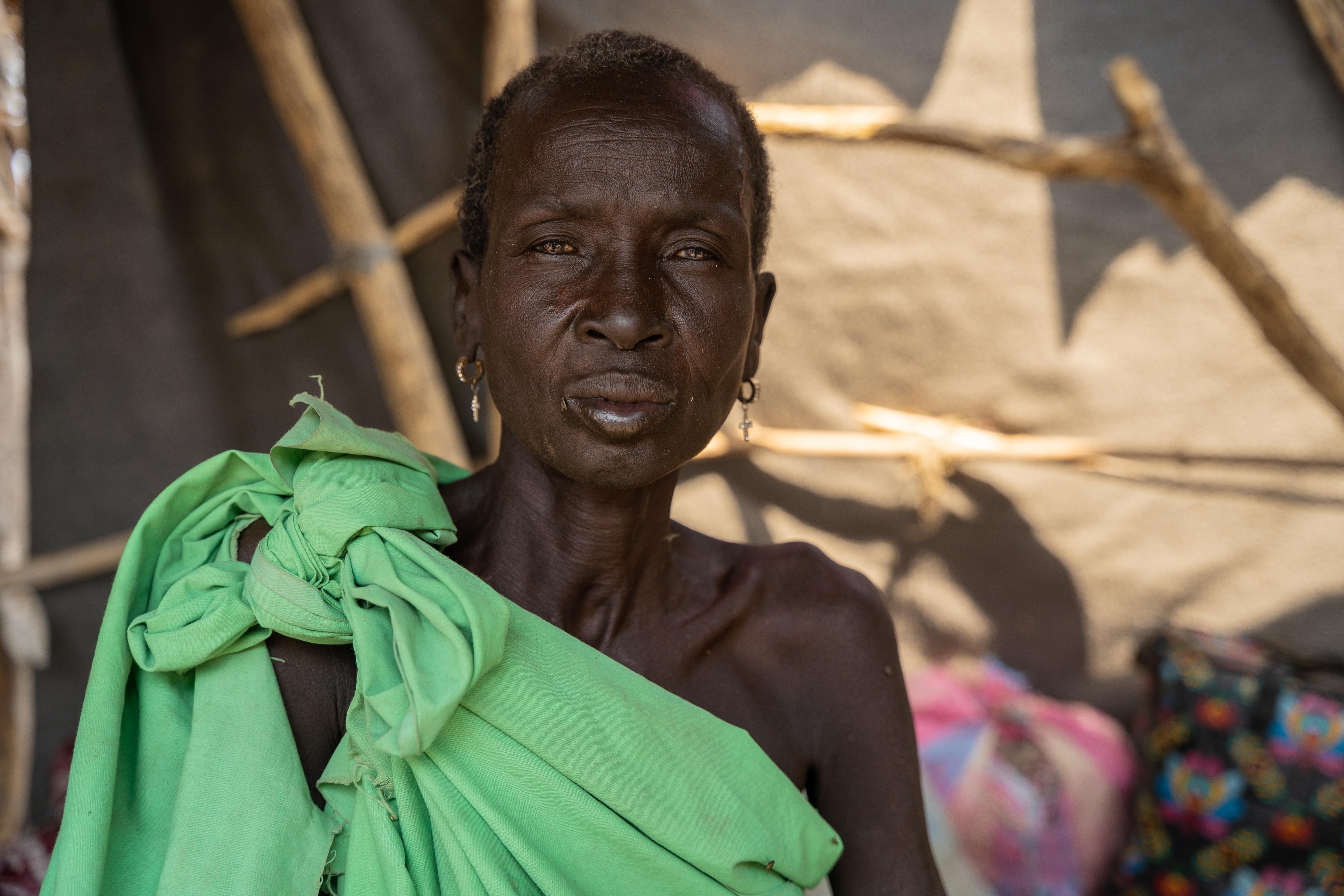 Portrait of Rebecah Chol, a former traditional birth attendant displaced from Lankien, sitting in a makeshift shelter in Yakuach, Jonglei State, South Sudan. 